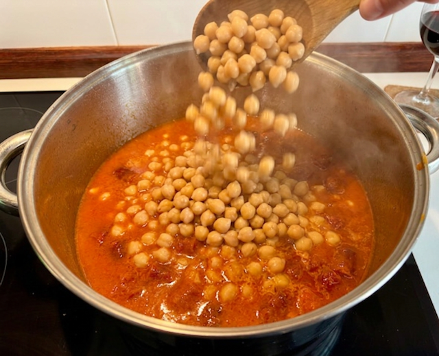 guiso de garbanzos con trozos de chistorra roja, virutas de jamón serrano y tallos de borraja