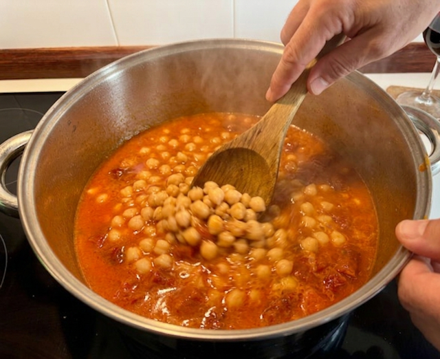 guiso de garbanzos con trozos de chistorra roja, virutas de jamón serrano y tallos de borraja